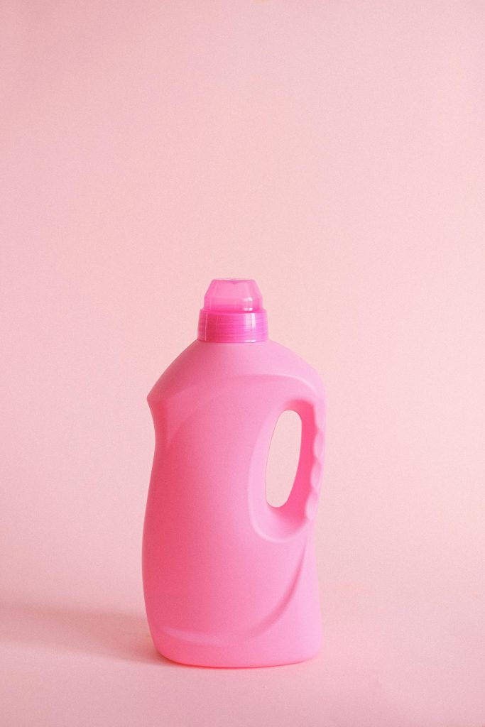Simple pink plastic detergent bottle on a pastel background, perfect for hygiene and cleaning concepts.